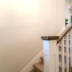 Square frame Indoor staircase of a home with white balusters brown handrail and newel