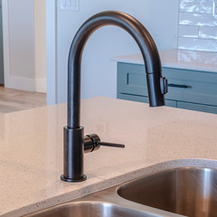 Square Black faucet and stainless steel double basin sink on kitchen island of home