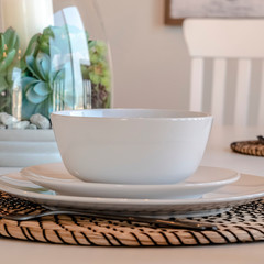 Photo Square Dining tableware and round placemat against candle and plant centerpiece