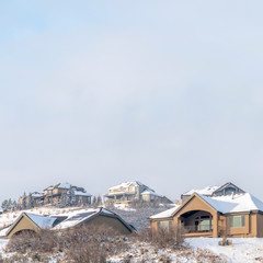 Square frame Houses with front gabled balconies on a snow covered hill at winter season