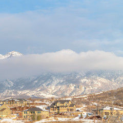 Photo Square frame Snowy mountain partially covered by thick clouds with houses in the foreground