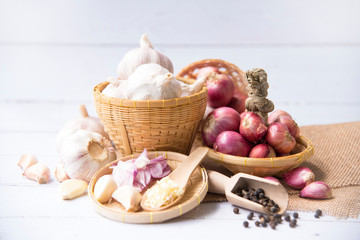 Garlic,shallot,Black pepper, fresh garlic, garlic clove, garlic bulb and shallot in a wooden basket on white wooden table, A herb and spice cloves or food ingredients, Place for text.
