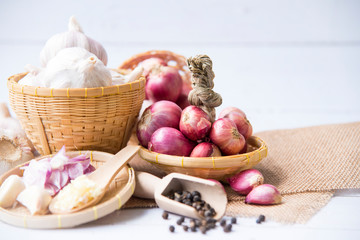 Garlic,shallot,Black pepper, fresh garlic, garlic clove, garlic bulb and shallot in a wooden basket on white wooden table, A herb and spice cloves or food ingredients, Place for text.