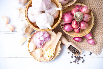 Garlic,shallot,Black pepper, fresh garlic, garlic clove, garlic bulb and shallot in a wooden basket on white wooden table, A herb and spice cloves or food ingredients, Place for text.