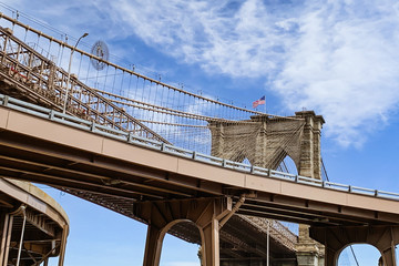 Brooklyn Bridge and American Flag Against Cloudy Blu Sky, New York City.