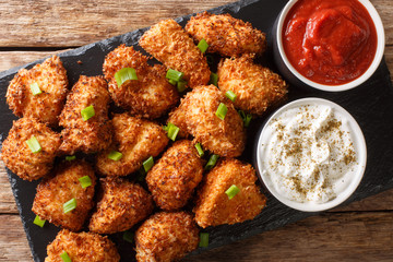 Crispy coconut chicken nuggets served with ketchup and mayonnaise close-up on a table. Horizontal top view
