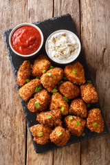 Deep-fried coconut breaded chicken with two sauces close-up on a slate board. Vertical top view