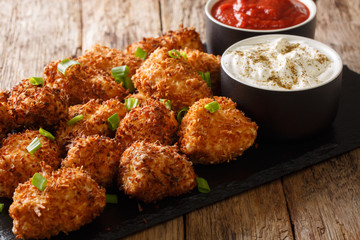Delicious chicken nuggets breaded with coconut served with ketchup and mayonnaise close-up on a slate board. horizontal