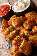 Coconut crispy chicken with two sauces close-up on a slate board. vertical