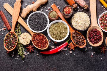 Spices and herbs over black stone background. Top view with free space for menu or recipes