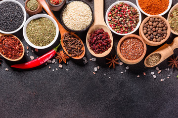 Spices and herbs over black stone background. Top view with free space for menu or recipes