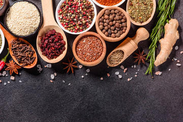 Spices and herbs over black stone background. Top view with free space for menu or recipes