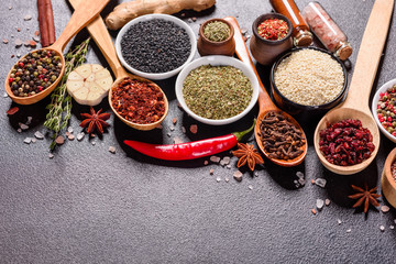 Spices and herbs over black stone background. Top view with free space for menu or recipes