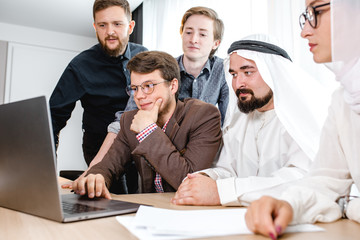 meeting with an Arab representative a group of young people at a laptop in the office