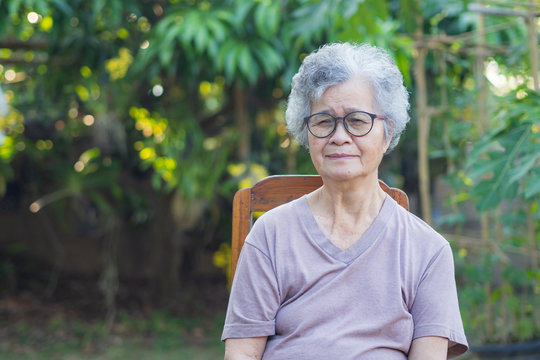 Elderly woman short white hair sitting on chair in the garden