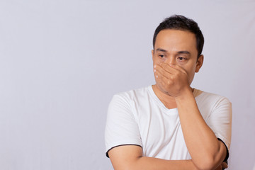 Asian youth expression wearing white T-shirt covered part of his mouth or face because he smelled something that smells or acts when he doesn't have a mask.