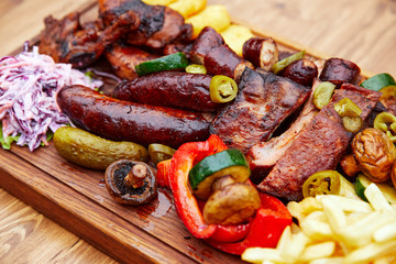 meat sausages and meat laid out on a board with potatoes and vegetables