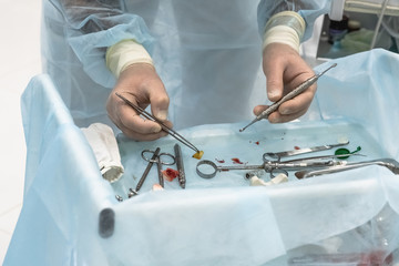 Close-up of the hands of a dentist surgeon who cuts off the barrier membrane during dental implantation