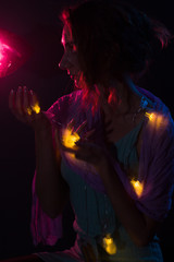 Young redhead Caucasian woman holding fairy lights portrait red background light