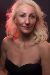 Fototapeta premium Portrait old woman in colorful bright lights. red and gold color, dark maroon background