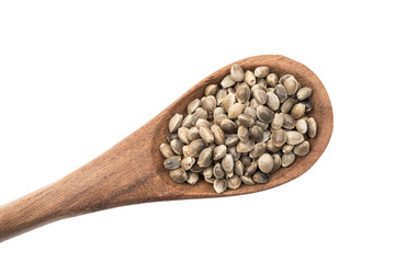Brown wooden spoon with hemp seeds from lower left corner seen directly from above and isolated on white background