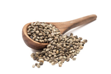 Brown wooden spoon with pile of hemp seeds seen obliquely from the front and isolated on white background