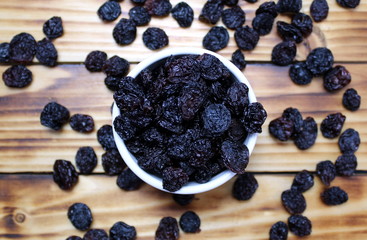 Black raisins in a white plate on a wooden table