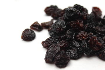 Small pile of black raisins on a white backgr - obrazy, fototapety, plakaty