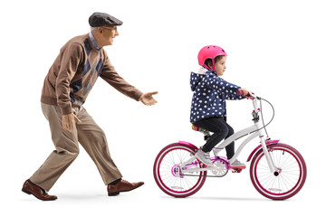 Grandfather teaching a granddaughter to ride a bicycle