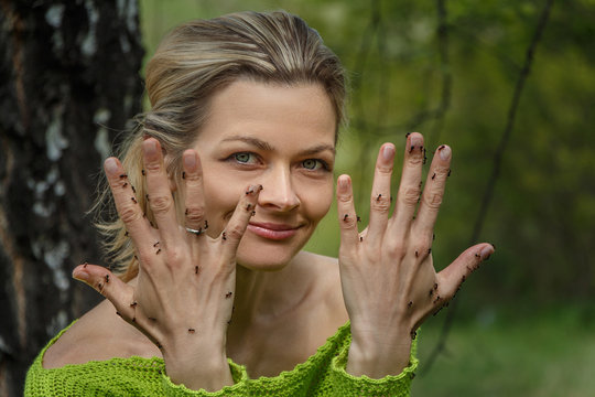 the woman in the woods in the summer shows a hand covered with ants