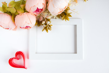 Holiday card for Valentine's Day. White frame, red paper hearts, a bouquet of pink flowers on a white background. Copyspace.