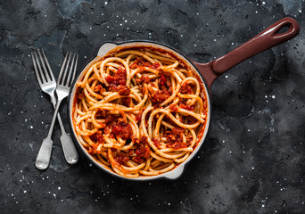 Traditional Roman pasta - bucatini amatricana in a pan on a dark background, top view