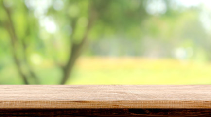 blurred background of green park in summer, Wood table top on shiny bokeh green background. For product display