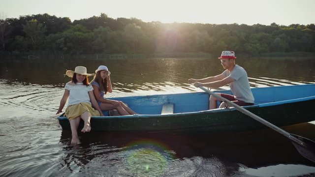 Young family sails in a wooden boat over the lake at sunrise, slow-motion video