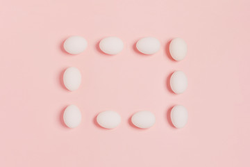 Happy Easter. Rectangular frame made of white eggs on pink background. Flat lay, top view, copy space.