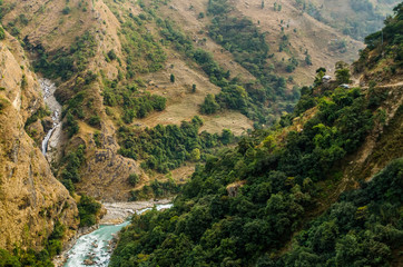 Fototapeta na wymiar Terrace fields and small houses in deep mountain valley over the Marshyangdi river near Jagat village. Annapurna circuit trek, Nepal.