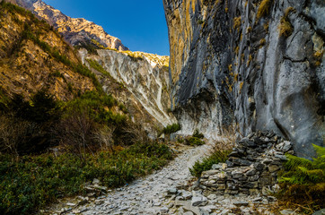 Mountain road carved inside a rocky slope in Marshyangdi river valley. Annapurna circuit trek, Nepal.