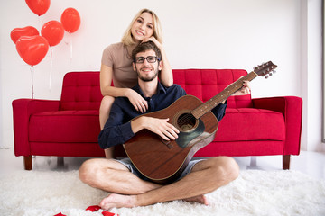 Caucasian couple resting and enjoying playing guitar together in the living room, leisure and activity concept.