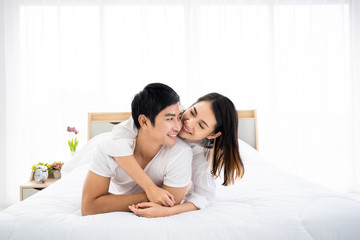 Beautiful Asian couple laying and talking together on the bed. Couple relationship concept.