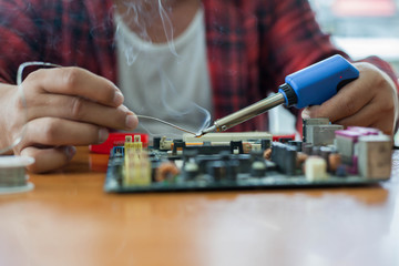  A man's hand holding that the soldering iron solder the chips into electronic circuit board.