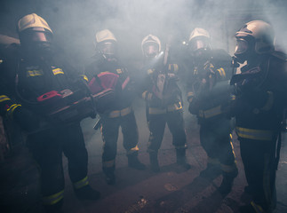 Group of firemen with gas masks standing in the middle of the chainsaw's smoke