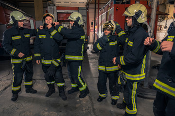 Firemen preparing for emergency service. Firefighters putting on gloves.