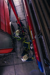Fototapeta na wymiar Firemen checking the fire engine inside the fire department from a bird perspective