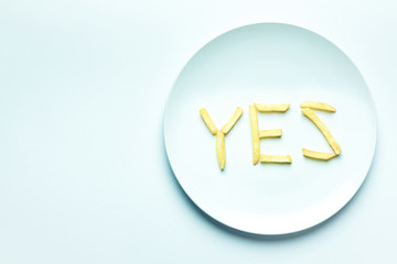 Top view of yes lettering from french fries on plate on white background with copy space