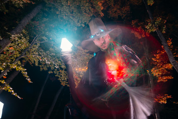 Wizard (mage) casting a spell with his magical staff while standing in an enchanted forest..