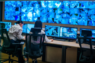 Female security guards working in surveillance room, monitoring cctv and discussing. - obrazy, fototapety, plakaty