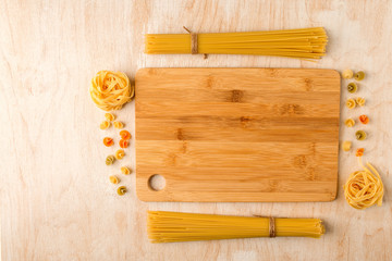 macaroni of different types on a wooden table and a cutting Board made of bamboo
