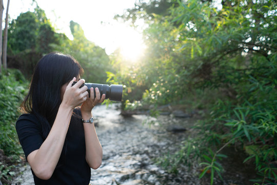 Asian woman photographer in nature. Taking pictures right side