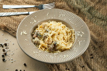 Homemade and fresh pasta chicken, mushroom and parmesan. Italian pasta tagliatelle in a beige ceramic plate on a rustic background in a composition with ingredients