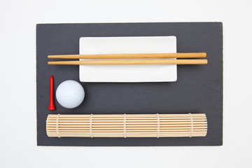 Rectangular slate plate with chopsticks for sushi and golf ball.